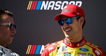 Joey Logano smiling while looking at AJ Allmendinger at Kansas.
