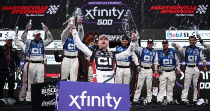Rudy Fugle (left) claps with William Byron (R) in Victory Lane at Martinsville Speedway while holding a NASCAR Cup Series Playoffs grid.