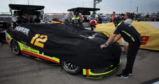 The cars of Ryan Blaney and Joey Logano are covered at Kansas. Rain washed out qualifying, which meant the starting lineup was set by the metric.